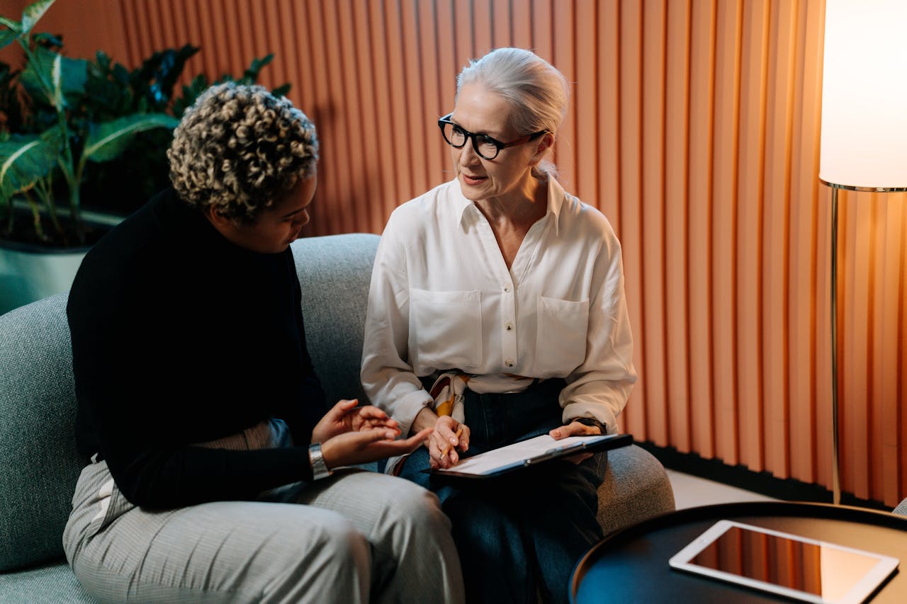 services-01 Two professional women engaged in a business discussion indoors with documents.