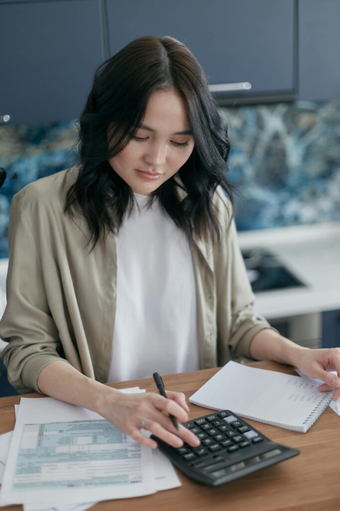 Services Woman using a calculator for budgeting and finance management at home desk.
